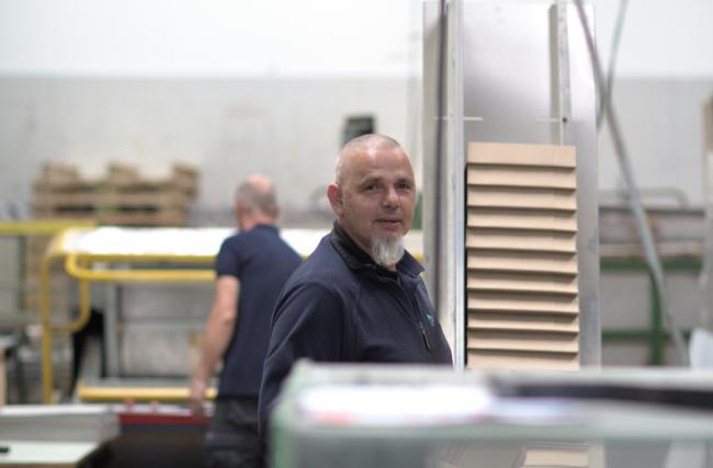 Employé collant les angles de couvercles en carton