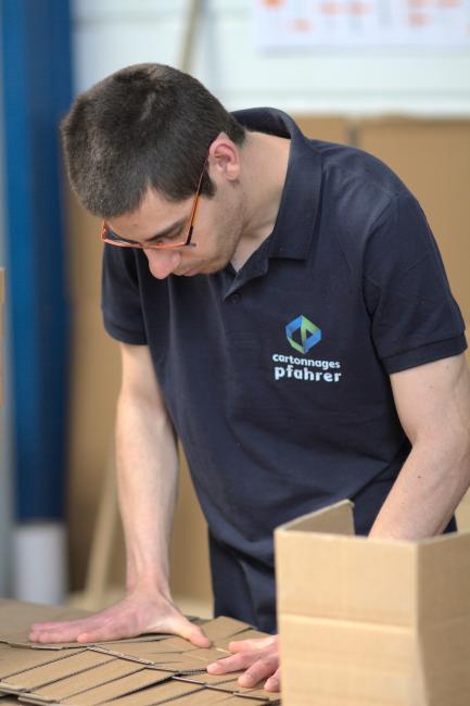 Employé œuvrant au pliage de boîte en carton